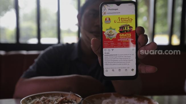 Warga menunjukkan sebaran promo makan gratis melalui gawainya di Soto Seger Boyolali Hj. Amanah, Lebak Bulus, Jakarta, Selasa (19/10/2021). [Suara.com/Angga Budhiyanto]