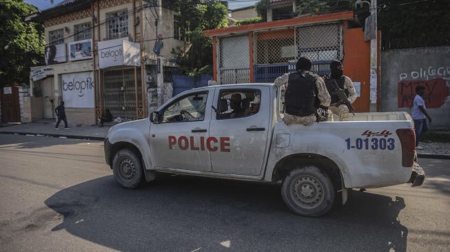 Polisi bersenjata menaiki mobil setelah jalan-jalan di ibu kota Haiti Port-au-Prince sepi menyusul seruan pemogokan umum yang diluncurkan oleh beberapa asosiasi profesional dan perusahaan untuk mengecam ketidakamanan di Port-au-Prince, pada (18/10/2021). [RICHARD PIERRIN / AFP]