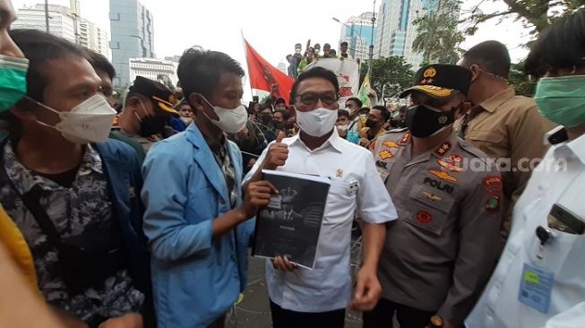 Moeldoko mengacungkan jempol saat menerima tuntutan dari mahasiswa yang berdemo memperingati tujuh tahun kepemimpinan Presiden Jokowi. (Suara.com/Yaumal)