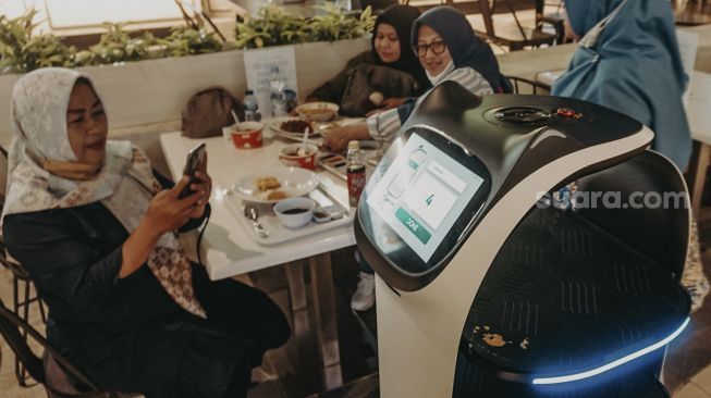 Pengunjung mengambil gambar Robot pramusaji “Bellabot” di Tangcity Mall, Kota Tangerang, Banten, Kamis (21/10/2021). [Suara.com/ Hilal Rauda Fiqry]