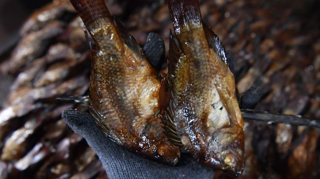 Seorang ibu menata ikan asap di Kampung Ikan Asap Penatarsewu binaan Pertagas di Sidoarjo, Jawa Timur, Rabu (20/10/2021). [ANTARA FOTO/Zabur Karuru]