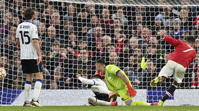 Striker Manchester United Cristiano Ronaldo (kanan) mencetak gol ketiga timnya selama pertandingan sepak bola grup F liga Champions UEFA antara Manchester United dan Atalanta di stadion Old Trafford, Manchester, Inggris, pada (20/10/2021). [PAUL ELLIS / AFP]