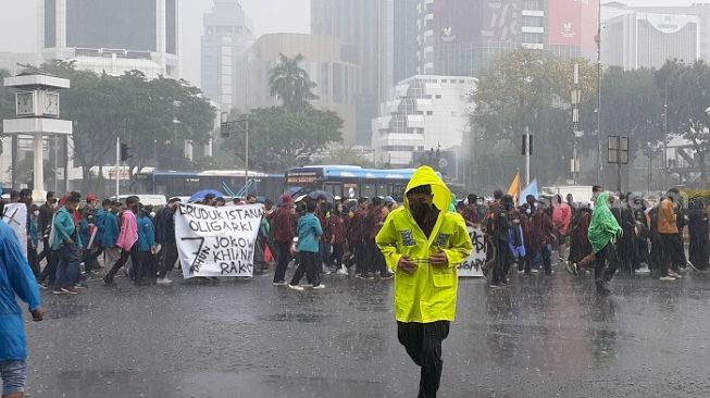 Massa BEM SI rela diguyur hujan saat melakukan longmarch demonstrasi 7 tahun kepemimpinan Jokowi. (Suara.com/Yaumal)