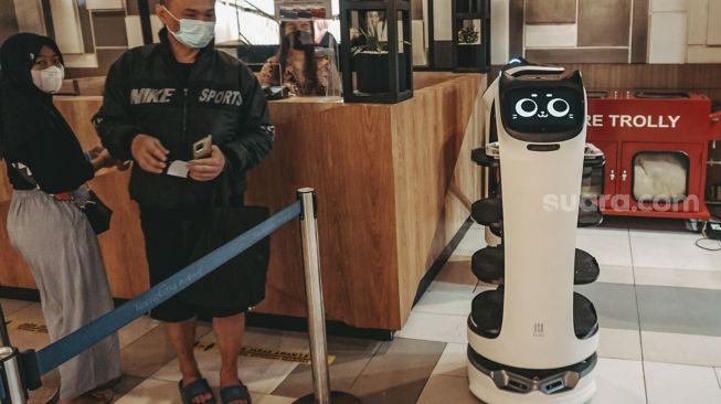 Pengunjung berdiri di samping  Robot pramusaji “Bellabot” di Tangcity Mall, Kota Tangerang, Banten, Kamis (21/10/2021). [Suara.com/ Hilal Rauda Fiqry]