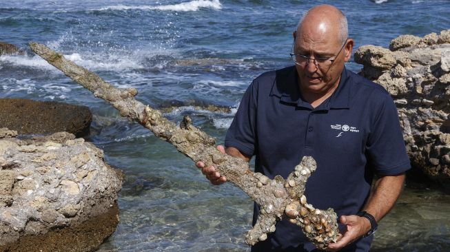 Jacob Sharvit dari Israel Antiquities Authority menunjukkan pedang kuno yang diyakini milik Tentara Salib, di Pelabuhan Israel Kaisarea, pada (19/10/2021).(19/10/2021). [JACK GUEZ / AFP]