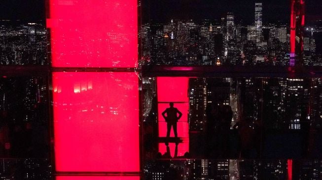 Influencer Rachel Wasley berpose di jendela saat anggota media menghadiri press preview untuk mengunjungi 'SUMMIT by Night' menjelang grand opening 'SUMMIT One Vanderbilt' di New York, pada (18/10/2021). [TIMOTHY A. CLARY / AFP]