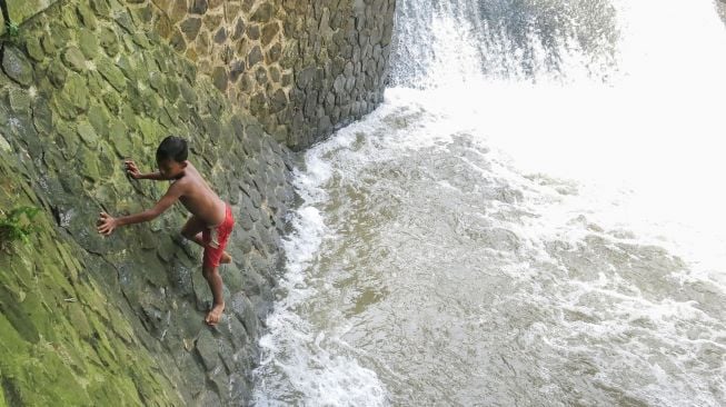 Seorang anak bermain di aliran Sungai Pesanggrahan, Bojonggede, Kabupaten Bogor, Jawa Barat, Jumat (22/10/2021).  ANTARA FOTO/Yulius Satria Wijaya