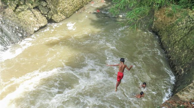 Seorang anak melompat ke aliran Sungai Pesanggrahan, Bojonggede, Kabupaten Bogor, Jawa Barat, Jumat (22/10/2021). ANTARA FOTO/Yulius Satria Wijaya