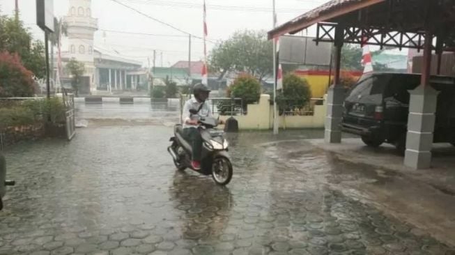 Ilustrasi - Salah satu warga berkendara saat hujan mengguyur wilayah Kota Palangka Raya. Antara/Rendhik Andika