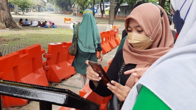 Salah satu pengunjung sedang scan kode batang PeduliLindungi di Taman Margasatwa Ragunan, Jakarta Selatan, Sabtu (23/10/2021). [ANTARA/Sihol Hasugian]