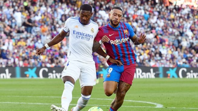 Bek Real Madrid, David Alaba berebut bola dengan penyerang Barcelona, Memphis Depay dalam laga Liga Spanyol di Camp Nou, Barcelona, Minggu (24/10/2021) malam WIB. [Josep LAGO / AFP]