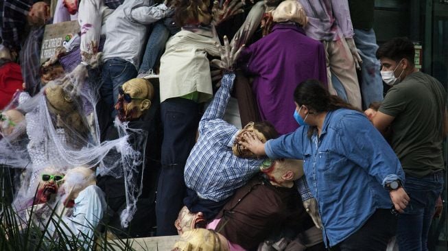 Warga menata sosok zombie yang dipajang di pusat perbelanjaan sebagai bagian dari dekorasi Musim Halloween di San Pedro Garza, Nuevo Leon, Meksiko, pada (22/10/2021). [JULIO CESAR AGUILAR / AFP]