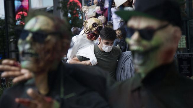 Warga menata sosok zombie yang dipajang di pusat perbelanjaan sebagai bagian dari dekorasi Musim Halloween di San Pedro Garza, Nuevo Leon, Meksiko, pada (22/10/2021). [JULIO CESAR AGUILAR / AFP]