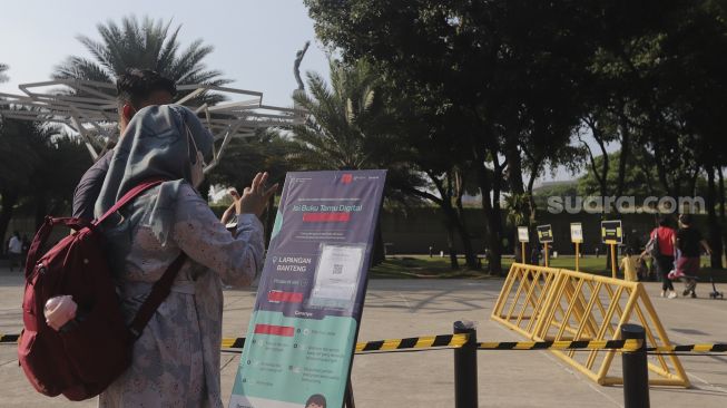 Warga memindai kode batang dari aplikasi PeduliLindungi sebelum memasuki area Lapangan Banteng, Jakarta, Minggu (24/10/2021). [Suara.com/Angga Budhiyanto]