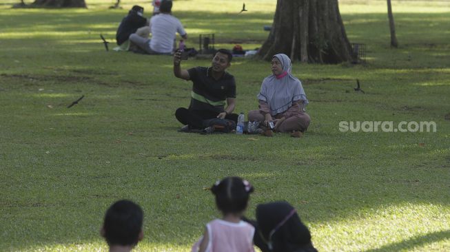 Warga berswafoto saat mengunjungi Lapangan Banteng, Jakarta, Minggu (24/10/2021). [Suara.com/Angga Budhiyanto]