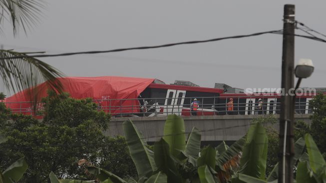 Petugas memeriksa kereta Lintas Rel Terpadu (LRT) yang mengalami kecelakaan di Ruas Cibubur-TMII, Jakarta, Senin (25/10/2021). [Suara.com/Angga Budhiyanto]