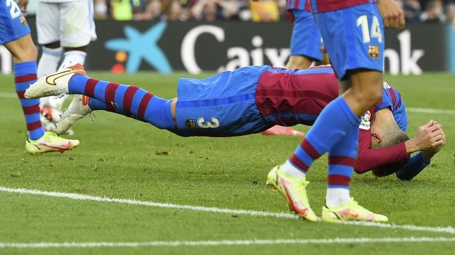 Bek Barcelona Gerard Pique terjatuh saat pertandingan sepak bola Liga Spanyol antara FC Barcelona dan Real Madrid CF di stadion Camp Nou, Barcelona, Minggu (24/10/2021). [JOSEP LAGO / AFP]