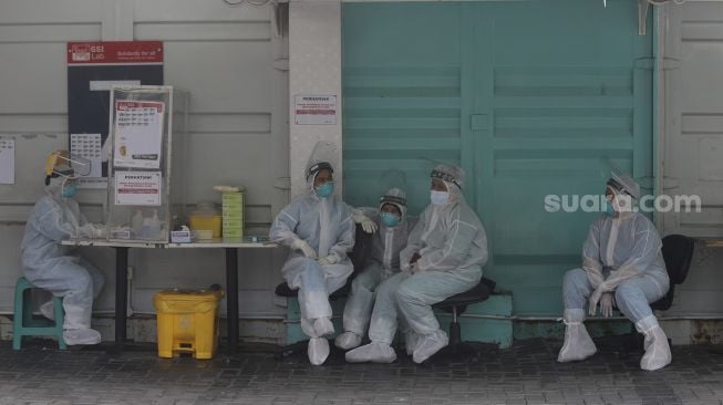 Petugas kesehatan beristirahat di sela melakukan tes usap (swab test) PCR di Jakarta, Senin (25/10/2021). [Suara.com/Angga Budhiyanto]