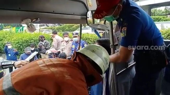 Penampakan petugas saat mengevakuasi sopir bus TransJakarta tewas kecelakaan di MT Haryono. (Suara.com/Yaumal)