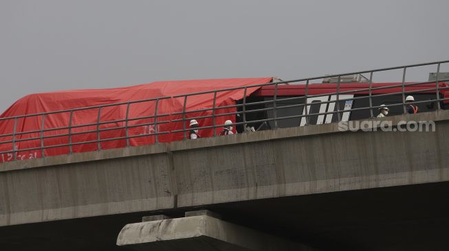 Petugas memeriksa kereta Lintas Rel Terpadu (LRT) yang mengalami kecelakaan di Ruas Cibubur-TMII, Jakarta, Senin (25/10/2021). [Suara.com/Angga Budhiyanto]