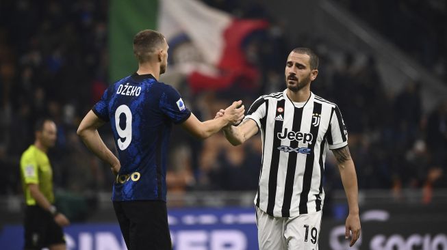 Pemain depan Inter Milan Edin Dzeko (kiri) dan pemain belakang Juventus Leonardo Bonucci berjabat tangan di akhir pertandingan sepak bola Serie A Italia antara Inter dan Juventus di stadion Giuseppe-Meazza (San Siro), Milan, pada (24/10/2021). [MARCO BERTORELLO / AFP]