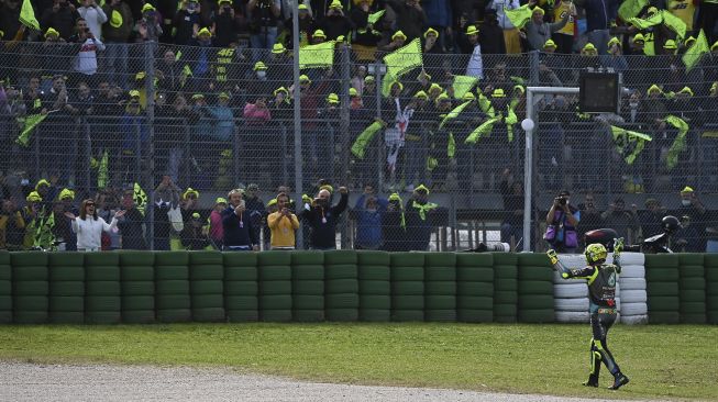 Pembalap Yamaha-SRT Italia Valentino Rossi berjalan menemui penggemarnya setelah Grand Prix MotoGP Emilia-Romagna di Sirkuit Dunia Misano Marco-Simoncelli, Misano Adriatico, Italia, pada (24/10/2021). [ANDREAS SOLARO / AFP]