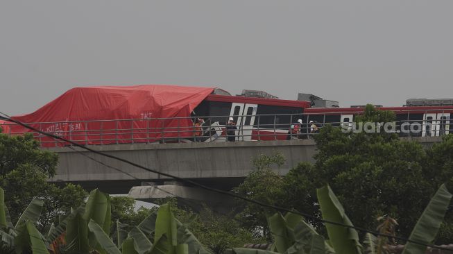 Petugas memeriksa kereta Lintas Rel Terpadu (LRT) yang mengalami kecelakaan di Ruas Cibubur-TMII, Jakarta, Senin (25/10/2021). [Suara.com/Angga Budhiyanto]