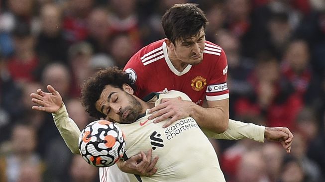 Gelandang Liverpool Mohamed Salah (kiri) bersaing dengan bek Manchester United Harry Maguire (kanan) selama pertandingan sepak bola Liga Premier Inggris antara Manchester United dan Liverpool di Old Trafford, Manchester, Inggris, Minggu (24/10/2021). [OLI SCARFF / AFP]