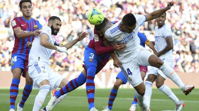 Bek Barcelona Gerard Pique (kedua kanan) bersaing dengan gelandang Real Madrid Casemiro selama pertandingan sepak bola Liga Spanyol antara FC Barcelona dan Real Madrid CF di stadion Camp Nou, Barcelona, Minggu (24/10/2021). [JOSEP LAGO / AFP]