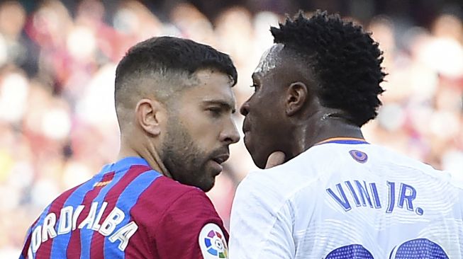 Bek Barcelona Jordi Alba (kiri) bertengkar dengan pemain depan Real Madrid Vinicius Junior selama pertandingan sepak bola Liga Spanyol antara FC Barcelona dan Real Madrid CF di stadion Camp Nou, Barcelona, Minggu (24/10/2021). [JOSEP LAGO / AFP]