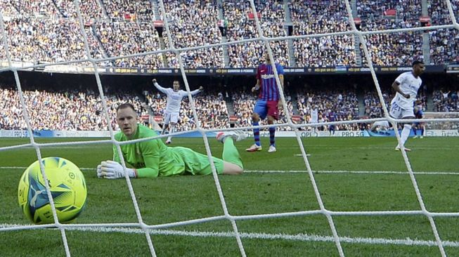 Penjaga gawang Barcelona asal Marc-Andre ter Stegen melihat bola setelah kebobolan dalam pertandingan sepak bola Liga Spanyol antara FC Barcelona dan Real Madrid CF di stadion Camp Nou, Barcelona, Minggu (24/10/2021). [JOSEP LAGO / AFP]