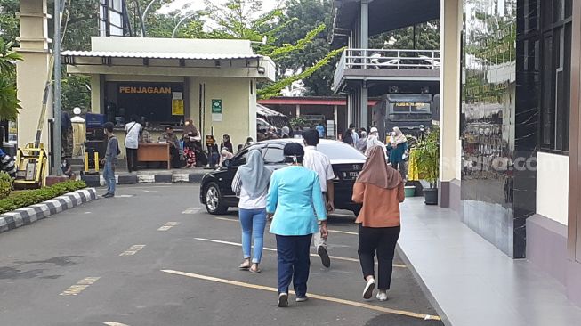 Seorang perempuan mengenakan seragam berwarna biru bertuliskan Rumah Sakit Abdul Radjak menyambangi Polres Metro Jakarta Pusat diduga diperiksa terkait kasus penganiayaan yang dilakukan Satpam RS hingga korban meninggal. (Suara.com/Yaumal)