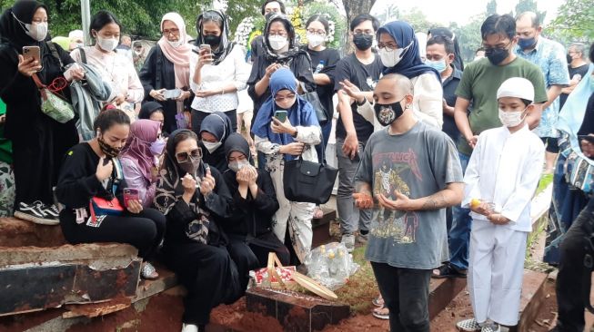 Chintami Atmanegara (duduk mengenakan masker putih) terlihat hadir di pemakaman Oddie Agam. Begitu juga, putranya, Dio Alif Utama (mengenakan koas abu-abu) di TPU Menteng Pulo, Jakarta, Rabu (27/10/2021). [Evi Ariska/Suara.com]