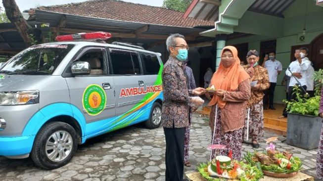 Bupati Bantul Abdul Halim Muslih (kiri) memotong tumpeng sebagai tanda peluncuran mobil ambulans hasil dari iuran masyarakat di Manding, Sabdodadi, Bantul, Rabu (27/10/2021). (Rahmat Jiwandono / SuaraJogja.id)