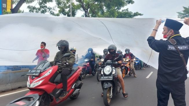 Pengendara motor melewati Bendera Merah Putih raksasa yang dibentangkan oleh massa untuk memperingati Hari Sumpah Pemuda di Jalan Kramat Raya, Jakarta Pusat, Kamis. ANTARA/Mentari Dwi Gayati