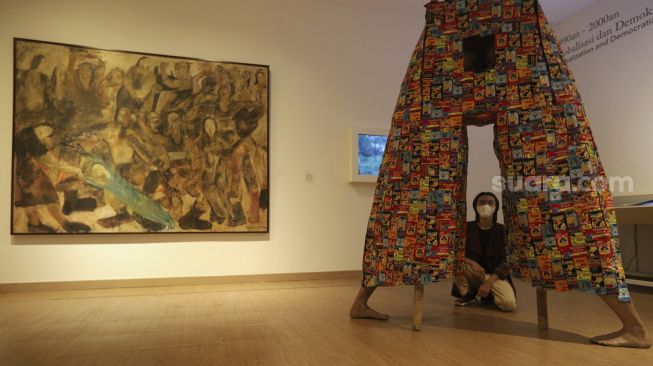 Pengunjung mengamati karya seni yang ditampilkan dalam Pameran Tetap Galeri Nasional Indonesia di Galeri Nasional, Jakarta, Kamis (28/10/2021). [Suara.com/Angga Budhiyanto]