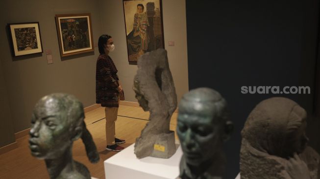 Pengunjung mengamati karya seni yang ditampilkan dalam Pameran Tetap Galeri Nasional Indonesia di Galeri Nasional, Jakarta, Kamis (28/10/2021). [Suara.com/Angga Budhiyanto]