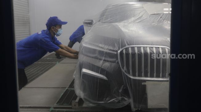 Teknisi melakukan proses perbaikan cat dan bodi mobil BMW saat peresmian Autoglad di Bengkel Autoglad, Jalan Raya Pekayon, Bekasi, Jawa Barat, Kamis (28/10/2021). [Suara.com/Angga Budhiyanto]