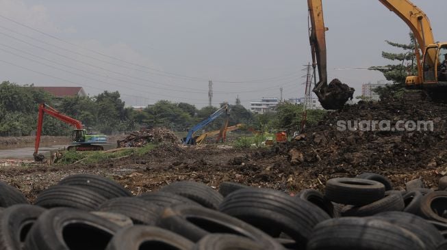 Petugas dari Suku Dinas Sumber Daya Air Jakarta Pusat mengoperasikan alat berat untuk melakukan pengerukan sedimen lumpur di sepanjang aliran Kanal Banjir Barat di kawasan Tanah Abang, Jakarta, Jumat (29/10/2021). [Suara.com/Angga Budhiyanto]