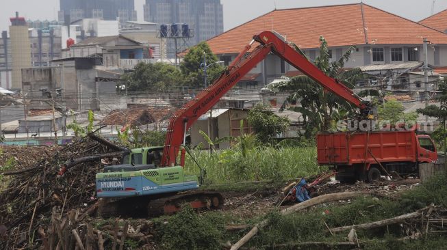 Petugas dari Suku Dinas Sumber Daya Air Jakarta Pusat mengoperasikan alat berat untuk mengangkut sampah di sepanjang aliran Kanal Banjir Barat di kawasan Tanah Abang, Jakarta, Jumat (29/10/2021). [Suara.com/Angga Budhiyanto]