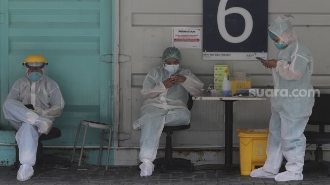 Petugas kesehatan beristirahat di sela melakukan tes usap (swab test) PCR di Jakarta, Jumat (29/10/2021). [Suara.com/Angga Budhiyanto]