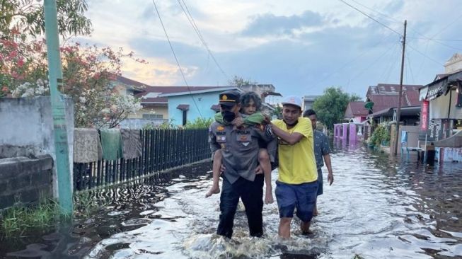 Kapolsek Dumai Gendong Lansia yang Terjebak Banjir