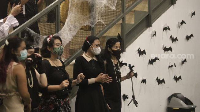 Pengunjung berdiri di dekat ornamen Halloween yang terpasang di M Bloc Space, Blok M, Jakarta, Minggu (31/10/2021). [Suara.com/Angga Budhiyanto]