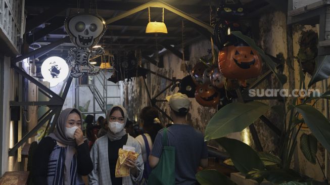 Pengunjung melintas di dekat ornamen Halloween yang terpasang di MBloc Space, Blok M, Jakarta, Minggu (31/10/2021). [Suara.com/Angga Budhiyanto]