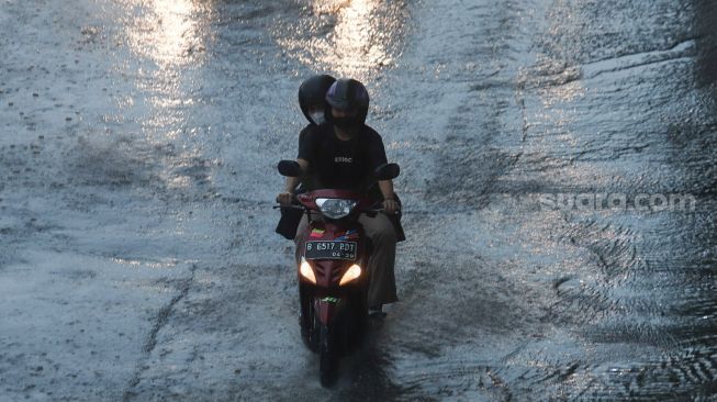 Pengendara motor melintas saat hujan di Jalan Gatot Subroto, Jakarta, Senin (1/11/2021). [Suara.com/Alfian Winanto]