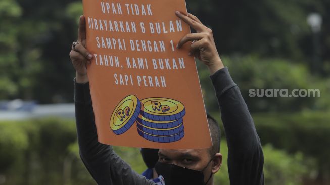 Sejumlah massa buruh membawa poster saat menggelar aksi unjuk rasa di kasawan Patung Kuda Arjuna Wiwaha, Jakarta, Senin (1/11/2021). [Suara.com/Angga Budhiyanto] 