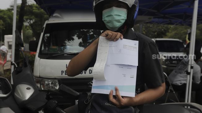 Seorang pengendara sepeda motor menunjukkan hasil uji emisi gas buang kendaraan di Lapangan Parkir IRTI Monas, Jakarta, Senin (1/11/2021). [Suara.com/Angga Budhiyanto]