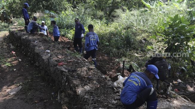 Petugas Sudin Sumber Daya Air memperbaiki tanggul di Kelurahan Cipinang Melayu, Jakarta, Selasa (2/11/2021). [Suara.com/Angga Budhiyanto]