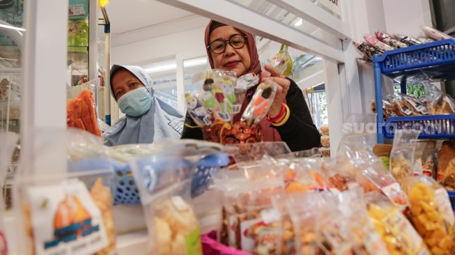 Seorang pelaku usaha mikro, kecil, dan menengah (UMKM) menjajakan dagangan di depan kiosnya di kawasan terpadu Stasiun Tebet, Jakarta Selatan, Selasa (1/11/2021). [Suara.com/Alfian Winanto]