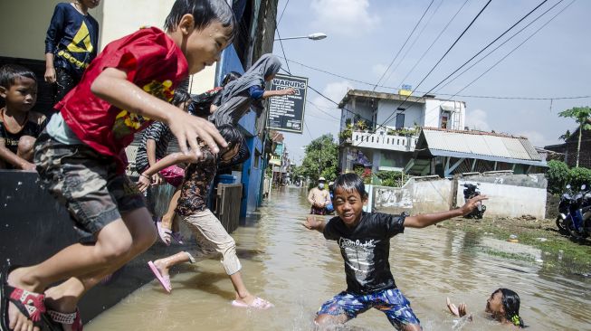 Sejumlah anak bermain pada genangan pada banjir di Dayeuhkolot, Kabupaten Bandung, Jawa Barat, Minggu (3/11/2021). ANTARA FOTO/Novrian Arbi